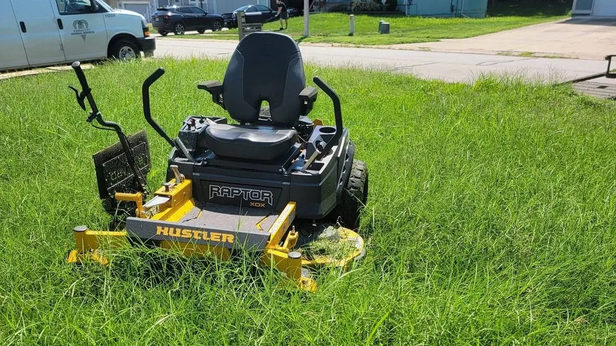 Zero turn mower parked in knee high overgrown grass on an underquoted lawn