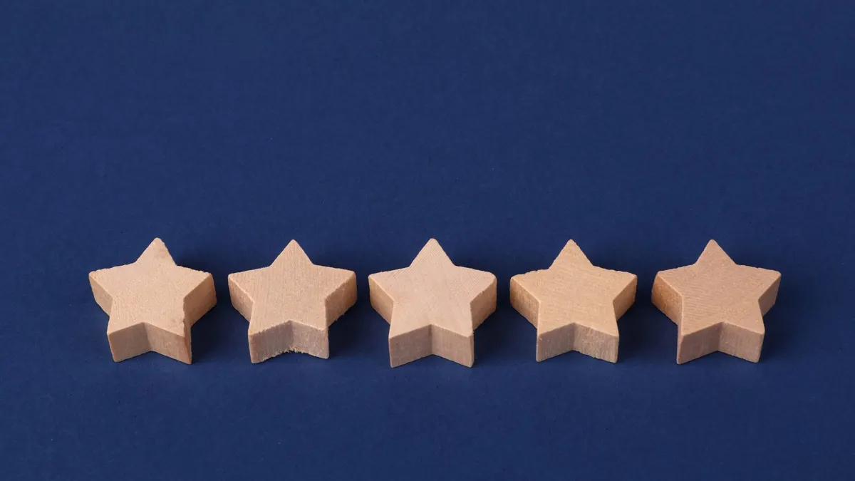 Five wooden stars in a row, a five star Google review for a lawn care business
