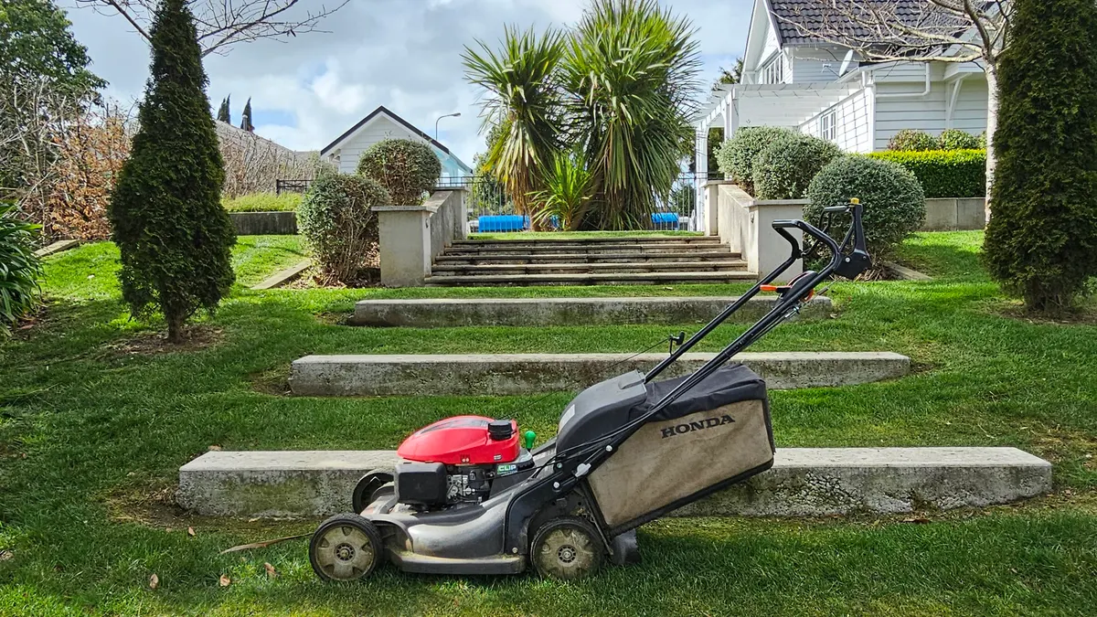 Mower on a lawn beside garden steps