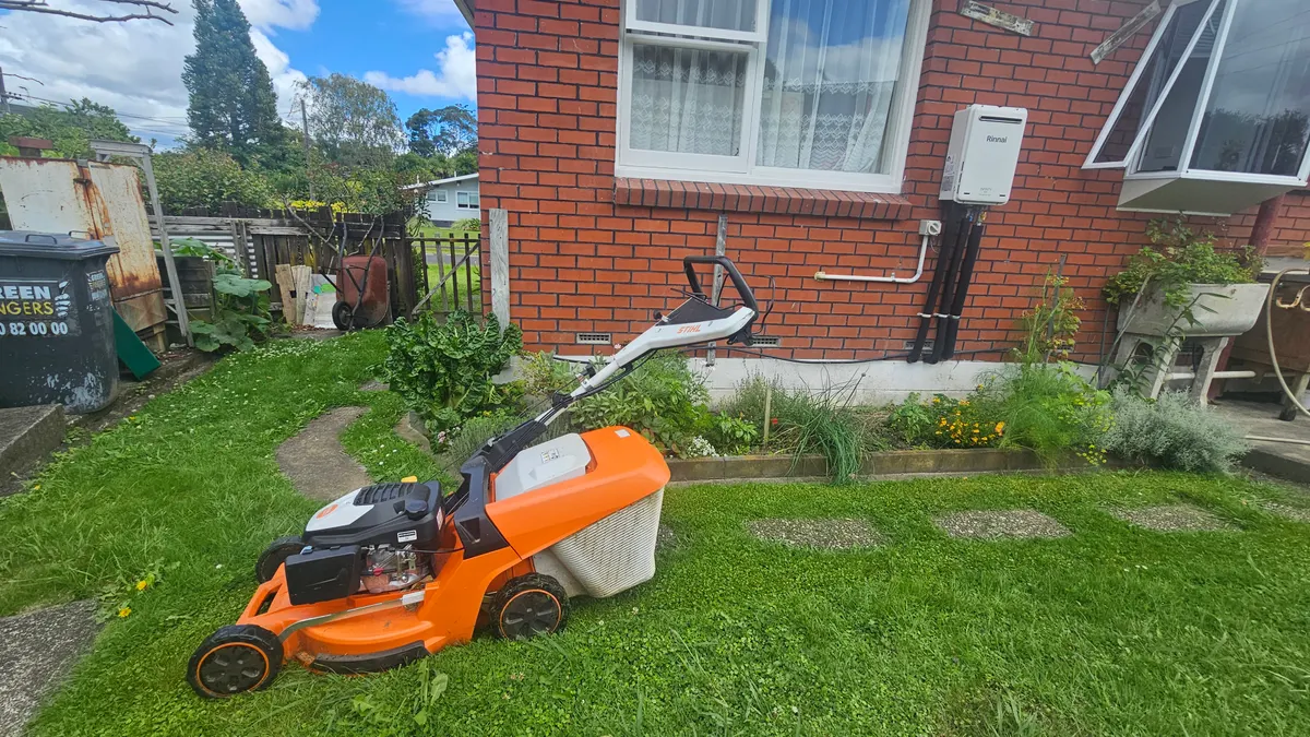 Mower on a lawn beside a brick house