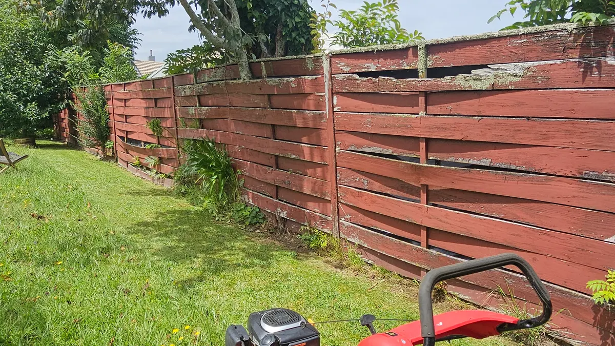 Mower against a red fence