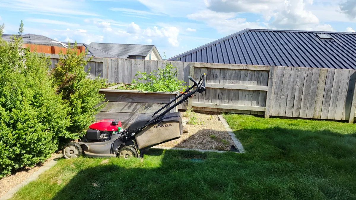 Mower on a back lawn by a new fence