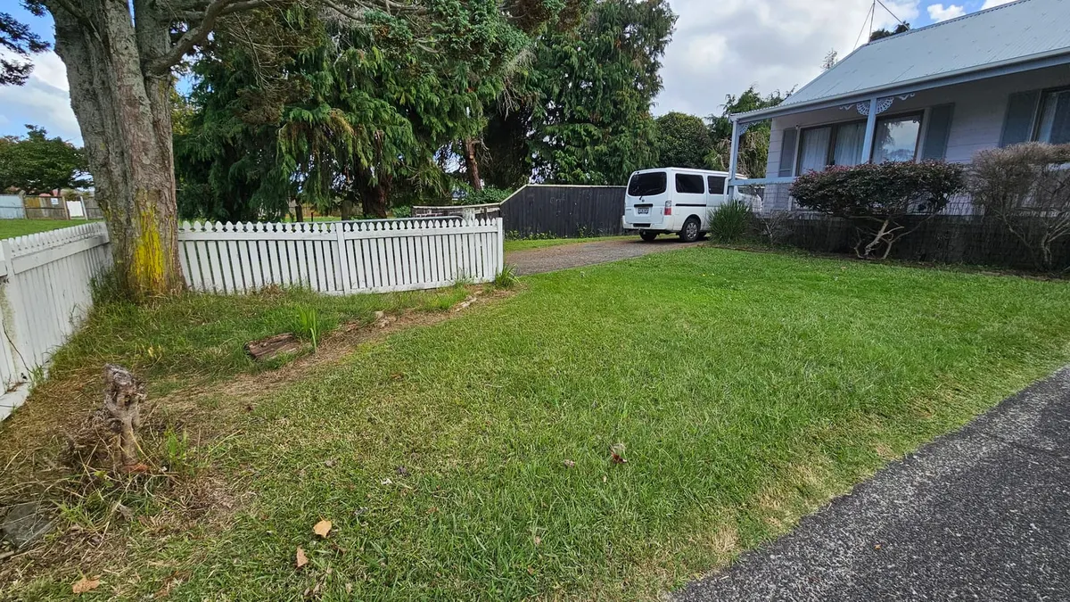 Freshly mown front lawn with a white picket fence and the work van in the driveway