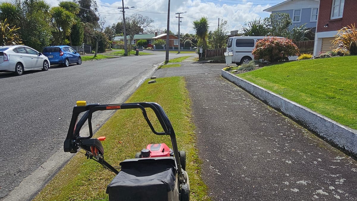 Push mower on a grass berm next to the footpath on a suburban street