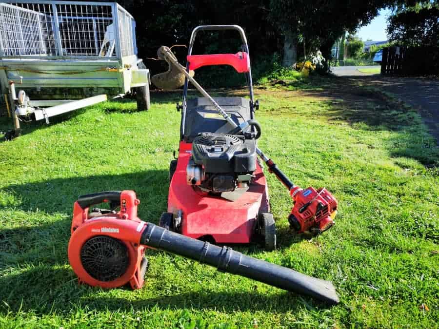 Push mower, Shindaiwa blower and line trimmer on a lawn with a trailer behind