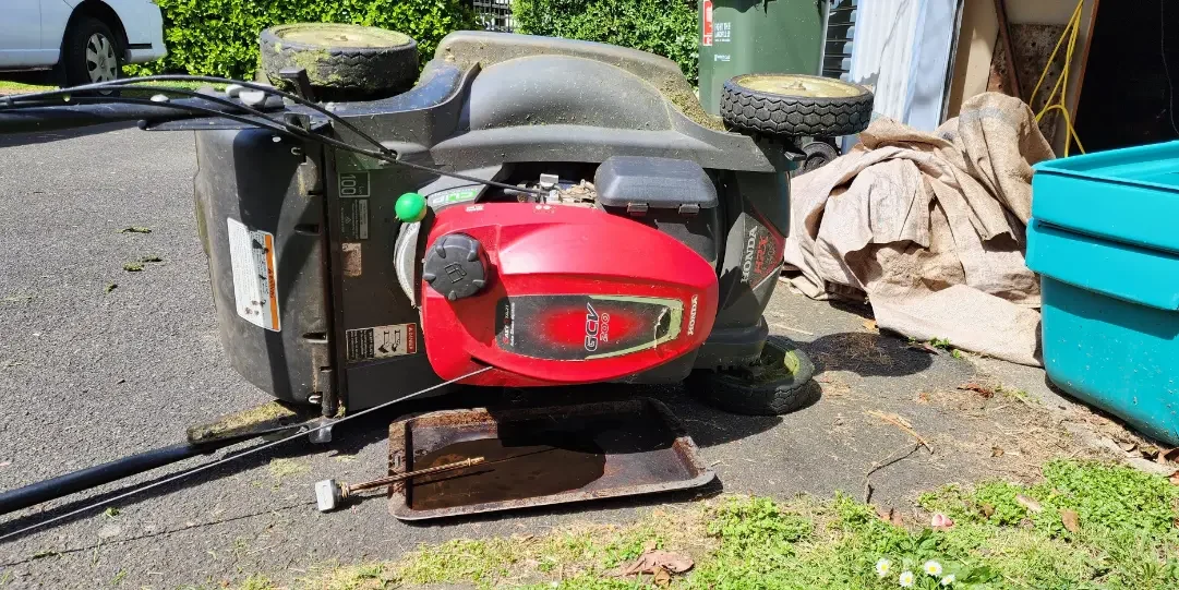 Lawn mowing tipped on side being drained of oil