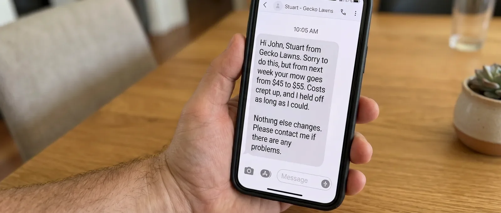 Phone showing a lawn care price increase text message sent to a customer