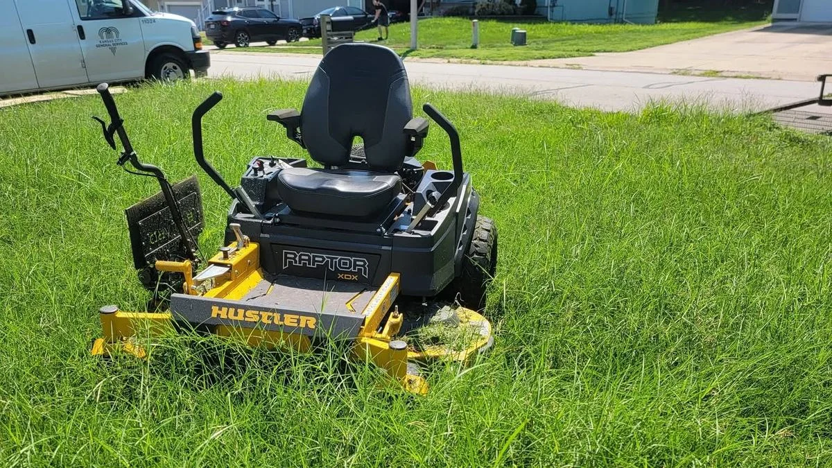 Zero turn mower parked in knee high overgrown grass on an underquoted lawn