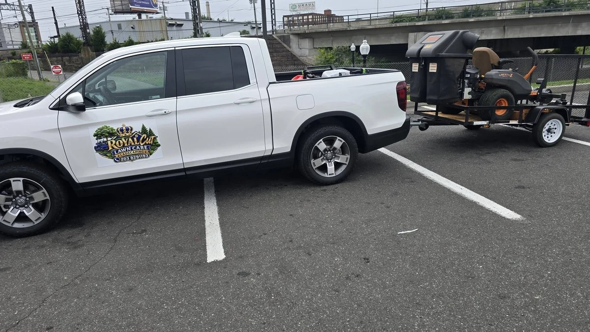 One man lawn care business truck and trailer parked on a job