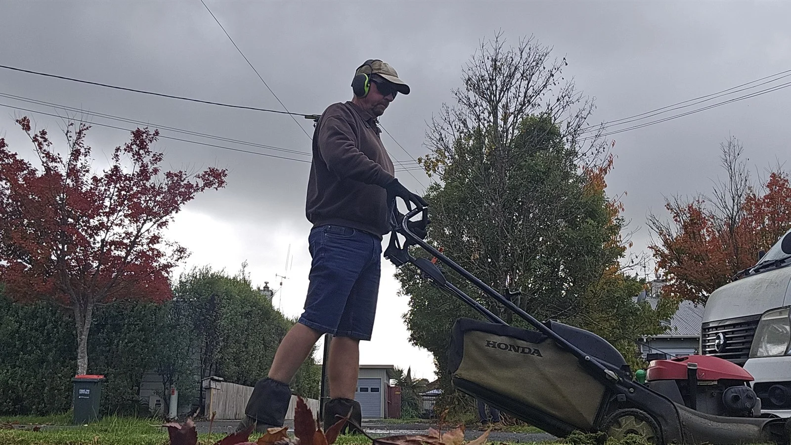 Lawn care operator mowing a front lawn with a Honda mower on an overcast day, turning up as promised