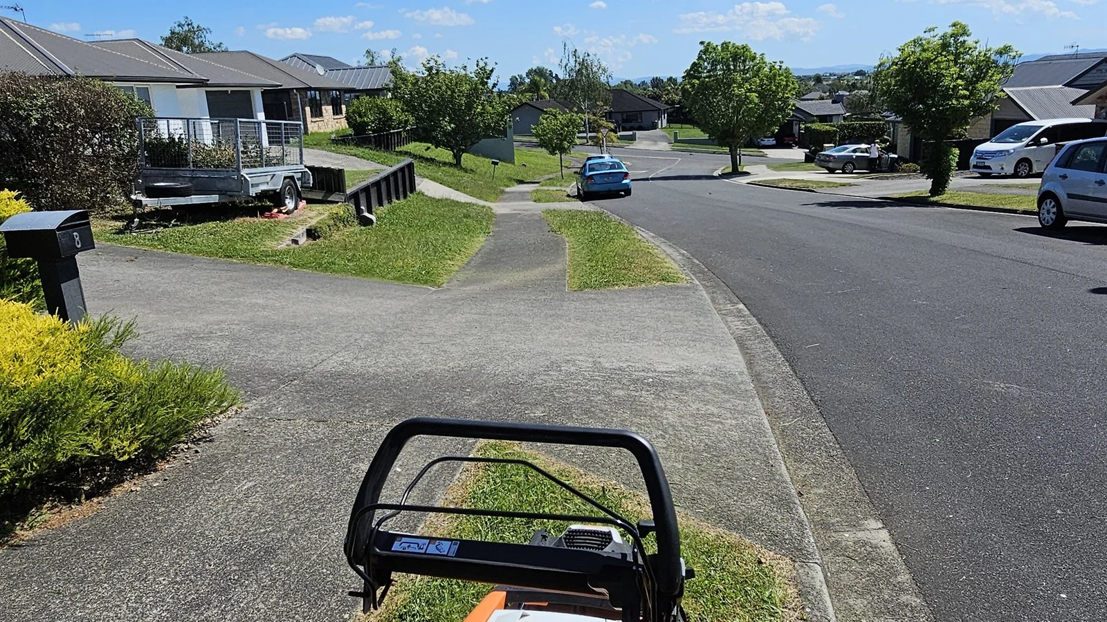 Mower handle in the foreground and a whole street of neighbours' houses ahead, the only lawn care referral program I have ever run