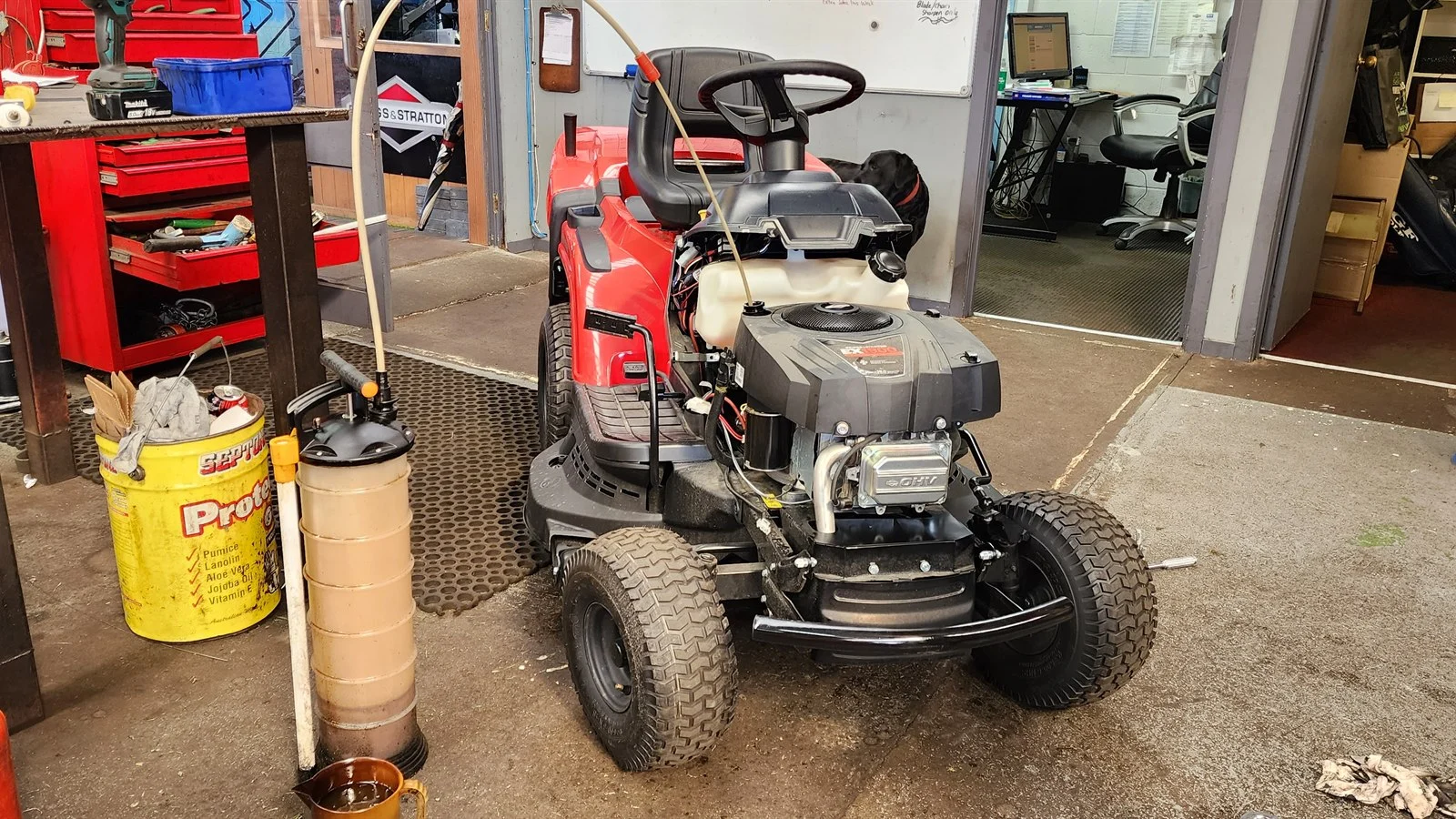 Ride-on mower having its oil changed in a workshop during the quiet winter months