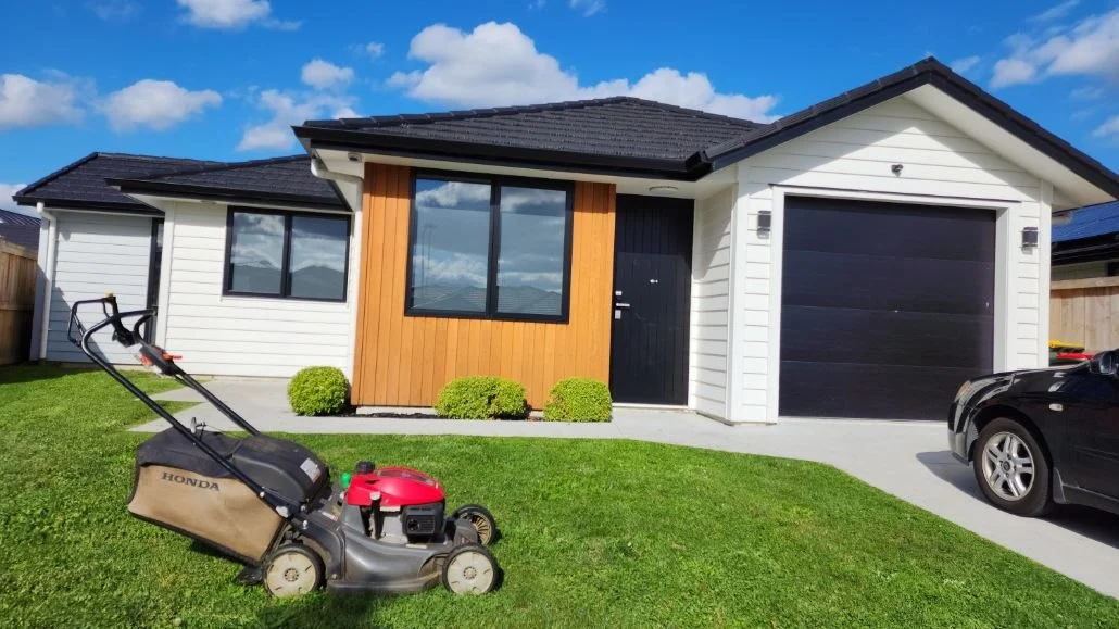 Push mower on a small front lawn of a new house, the kind of job that fits a lawn mowing side hustle evening