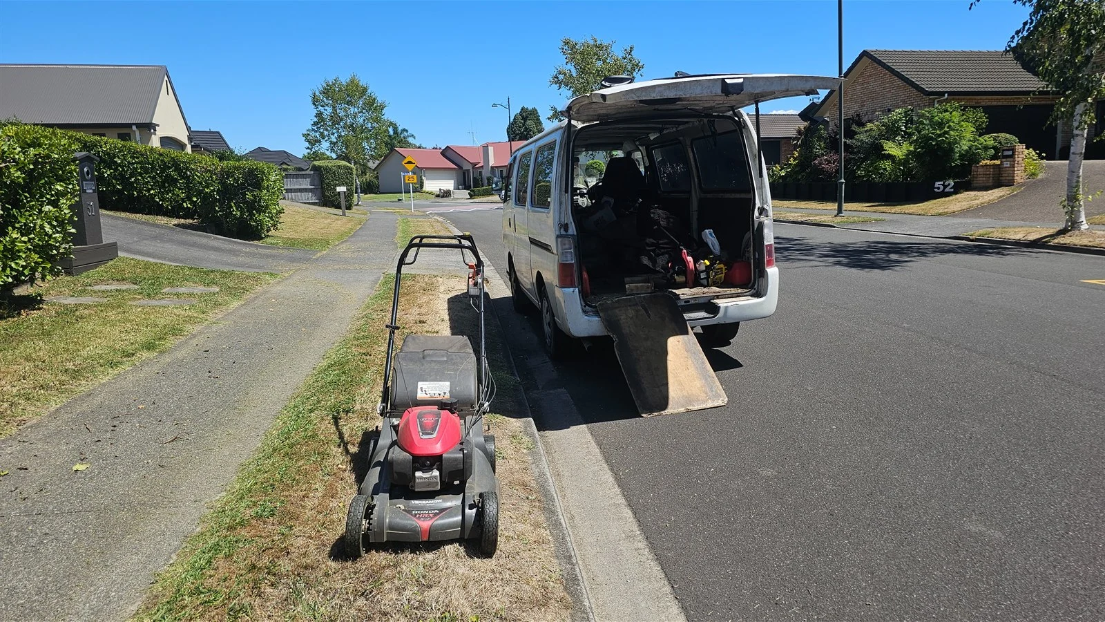 Mower on the berm of a quiet suburban street, a lawn mowing side hustle round built inside one area